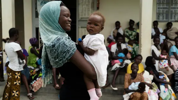 Anirworth Winnie, 17, holds her 7-month-old daughter, Delight, outside the UNICEF-supported Health Center in Nyaruvur, West Nile, Uganda. 