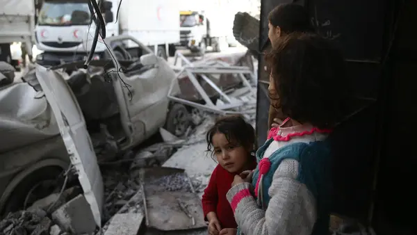 Children watch as a joint UNICEF, United Nations and Syrian Arab Red Crescent convoy of 46 trucks transporting food aid arrive in Eastern Ghouta on March 5, 2018.