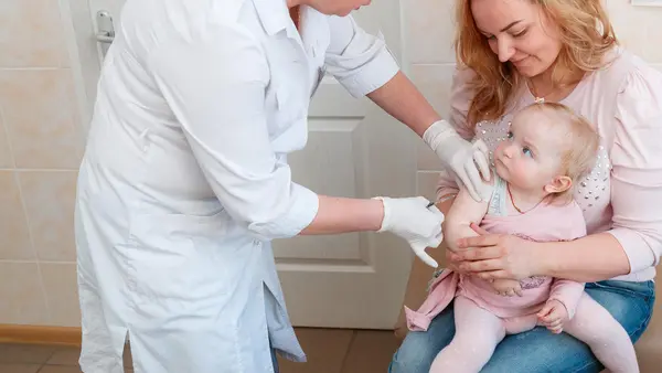 Sitting on her mother's lap, 1-year-old Dana didn't cry while getting her first dose of measles, mumps and rubella (MMR) at Children's Policlinic No. 1 in Obolon district, Kyiv, Ukraine in 2018.  