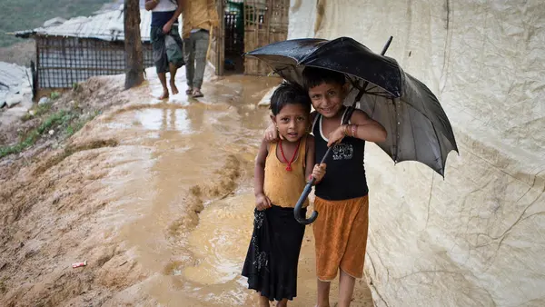 children smile as they shelter from the rain in Balukhali-Kutupalong, a refugee camp sheltering over 800,000 Rohingya refugees in Cox's Bazar, Bangladesh. 