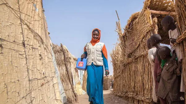 Aisha, a UNICEF-supported polio team vaccinator, walks through Muna Garage IDP camp in Maiduguri, Borno State, northeast Nigeria in January 2018.