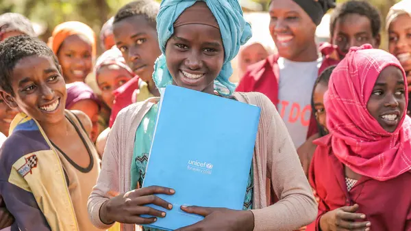Surrounded by her classmates, a girl holds her UNICEF notebook at Shawe Primary School, Harana Buluk Woreda, in Ethiopia's Oromia Region in 2019.