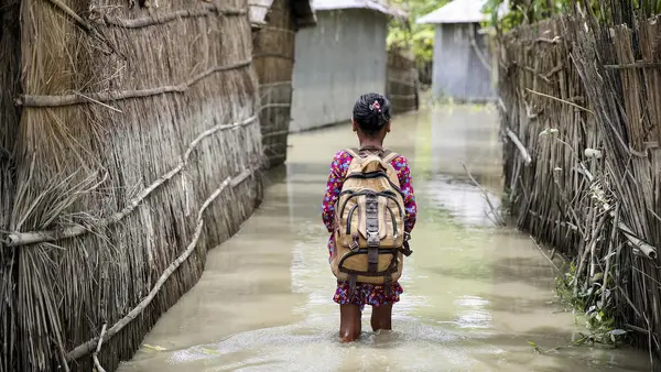 A child wades through flood water on her way to school in the Kurigram district of northern Bangladesh during monsoon season, August 2016.