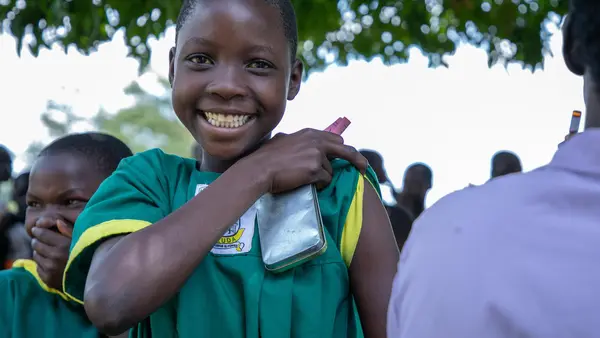 A happy girl prepares for her immunization against measles, mumps, rubella and polio during a nationwide campaign run by the Ugandan Government with support from UNICEF and WHO.