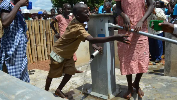 Children in Guinea gather water from a UNICEF-installed water pump in N’Zerekore