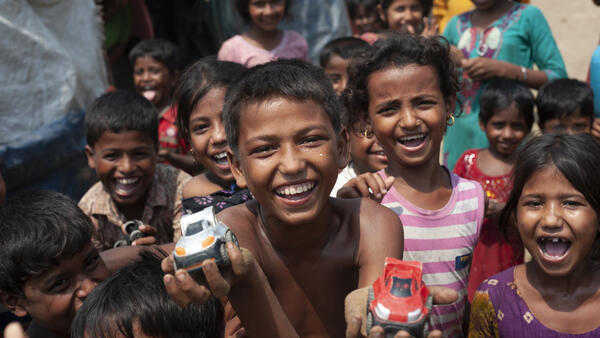 Mohammad Rifat, 12, (shirtless, center) and his friends race toy cars down a sandy stretch of trail in Shamlapur camp, Cox's Bazar District, Bangladesh on April 22 2018