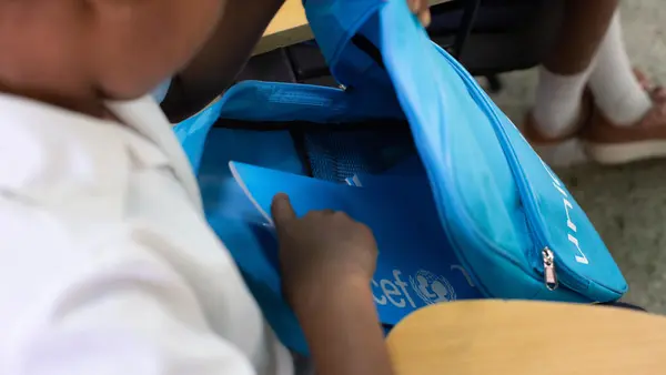 Child Putting Books into UNICEF Backpack
