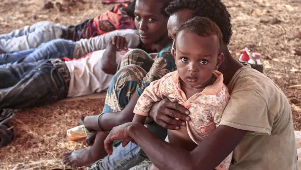 An Ethiopian refugee who fled fighting in Tigray province sits holding a child in a hut at the Um Raquba camp in Sudan's eastern Gedaref province, on 16 November 2020.