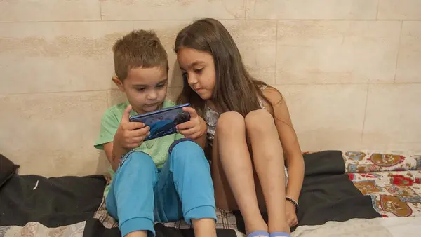 Andrej Madjupaj (4years) and Andjela Madjupaj (6 years) are playing a game on their phone, in their home in Roma settlement in Serbia.