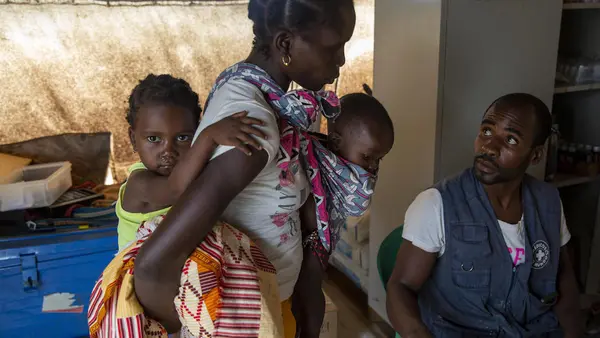 Eliza Arnaldo, 20, carries her children Natalia , 3, and Dominiqo, 6 months, to a UNICEF health center after they became feverish in the Ndjenja resettlement camp, Mozambique, March 4, 2020.
