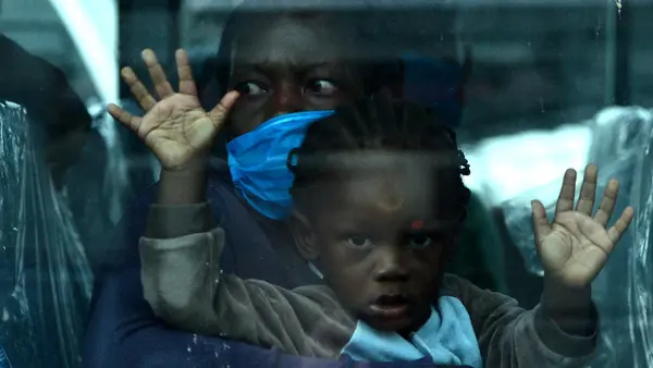 A migrant child and her mother on a bus headed to Toncontin international airport in Honduras, where they will be tested for COVID-19 and quarantined for two weeks.