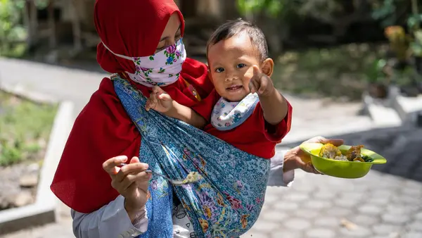 Dini feeds her year-old son Abdullah at their home in Paseban village, Central Java province, Indonesia.