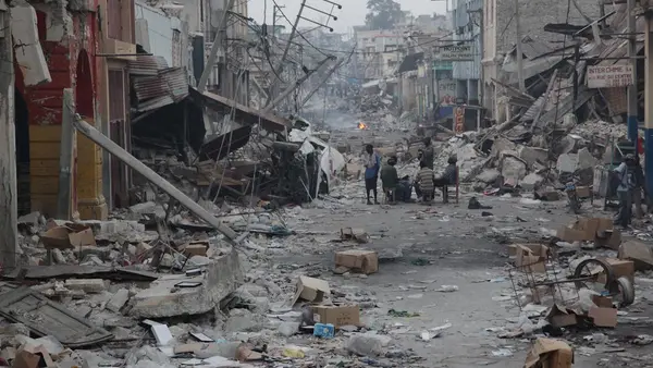 On January 19, 2010, men gather at a table and chairs set up in the middle of a street devastated by the earthquake, in Port-au-Prince, Haiti's capital.