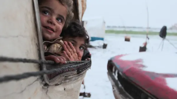 On 12 February 2020, children peer out from a tent at a recently established informal settlement which continues to receive newly displaced families from southern Idlib and rural Aleppo governorates in northwest Syrian Arab Republic.