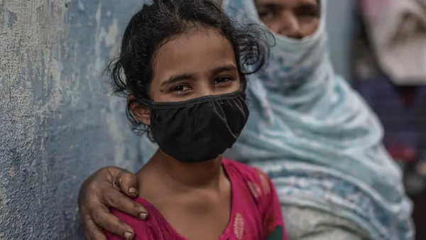 Mekak, 11, sits with her grandmother near a community toilet in the slums of Mumbai, India. UNICEF and partners are working to sustain urban slum sanitation and preparedness of schools during the COVID-19 public heatlh crisis. 