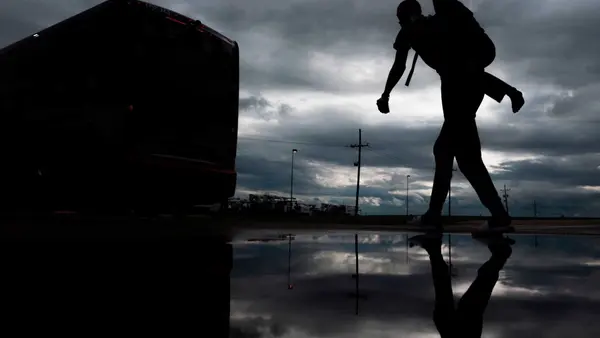 A man carries a child on his back as he walks to board a bus for evacuation before the arrival of Hurricane Laura in Lake Charles, Louisiana on August 25, 2020. 