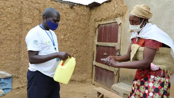 Man with a Container Helps Woman Wash Hands