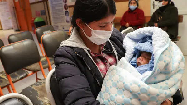 In the city of El Alto, Bolivia, Julia Condori cradles her son, Aaron, as they wait their turn in the UNICEF-supported Mercedes Health Center for the child’s latest round of vaccinations.