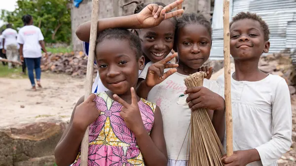 A group of young children from Kinshasa, Democratic Republic of the Congo, pause their clean-up activities to take a photo. The group, who range in age from 4 to 18, meet every Saturday morning to remove waste and discarded debris from their neighborhoods