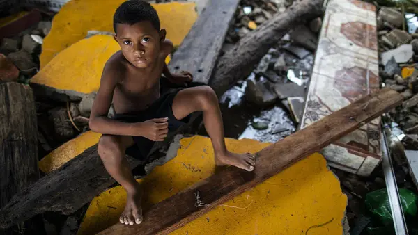 A boy in Bilwi, Nicaragua, sits on what remains of the family home in the wake of Hurricane Iota.