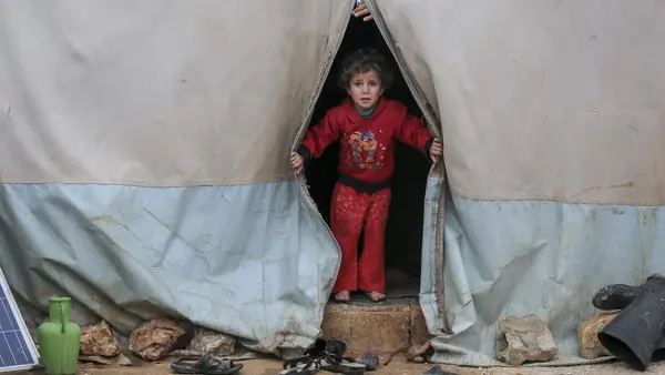 On 19 January 2021, a child looks out a tent in Kafr Losin Camp in northwest Syrian Arab Republic. UNICEF is working with partners to provide displaced children in Syria with the supplies and services they need to survive and thrive. 