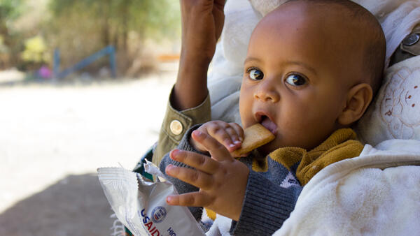 An infant eats a nutritional biscuit supplied by UNICEF as part of ongoing relief efforts for children and families displaced by violence in Ethiopia's Tigray region.