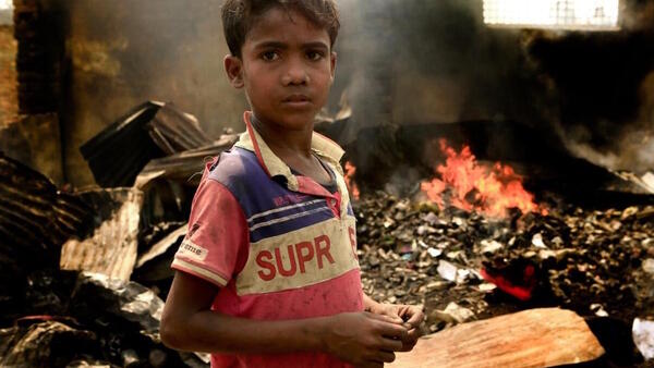 On March 23, 2021, 10-year-old Rezwan stands in the fire-damaged wreckage of the Balukhali area of the Rohingya refugee camps in Cox's Bazar, Bangladesh. 