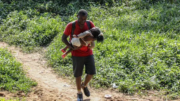 A father and child arrive in Bajo Chiquito, Panama, after crossing the Darien Gap, one of the most dangerous migration routes in the world.