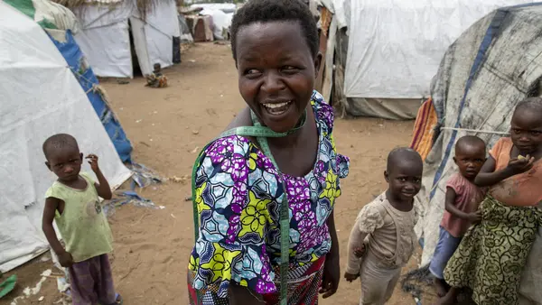 Jeannette Niyibigira, a seamstress and beneficiary of a micro-credit scheme funded by UNICEF and implemented by partner Faith in Action, greets fellow residents at a camp for internally displaced families in Gatumba, near Bujumbura, Burundi.