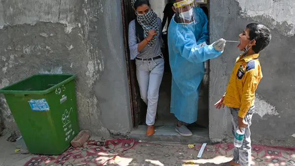 A medical worker takes a swab sample of a boy for a Reverse Transcription Polymerase Chain Reaction (RT-PCR) test at a COVID-19 testing center in Ghaziabad, India on April 29, 2021. 
