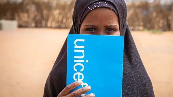 A student peeks out from behind her UNICEF notebook in Mbera refugee camp in southeastern Mauritania in 2021.
