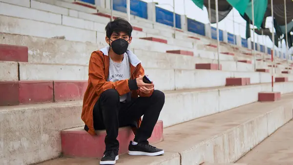 Andre, 14, sits in the stands of a repurposed sports stadium in Carabayllo, a district in the north of Lima, Peru, while he waits for his scheduled appointment at the UNICEF-supported Community Mental Health Center that occupies one of the buildings. 