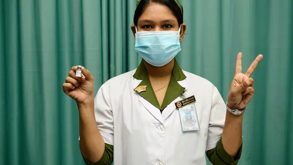 A trained vaccinator at Kurmitola General Hospital, Dhaka, Bangladesh, flashes V for victory — also V for vaccine — as COVID-19 vaccinations ramp up in the country, with support from UNICEF and the COVAX Facility.