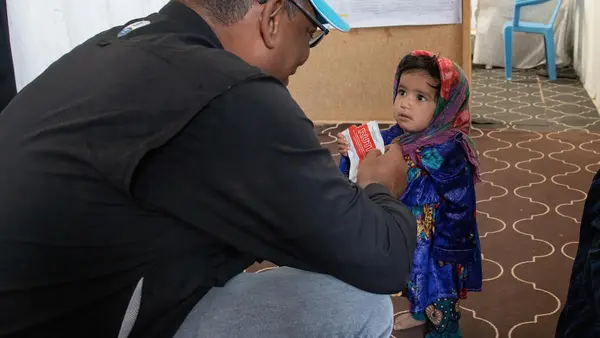 UNICEF Representative in Afghanistan Hervé Ludovic De Lys greets a girl enjoying a packet of Ready-to-Use Therapeutic Food at a clinic in the Sabz-e-Shark IDP camp in Herat on September 29, 2021.