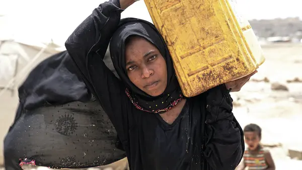 Ashwaq, 14, whose family was displaced from Saada, Yemen, carries water in the Khamir settlement in Amran.
