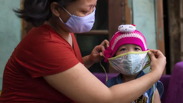 On June 14, 2020, a mother puts a mask on her 3-year-old daughter, Fatima, before leaving their home in Bekasi, West Java province, Indonesia. 