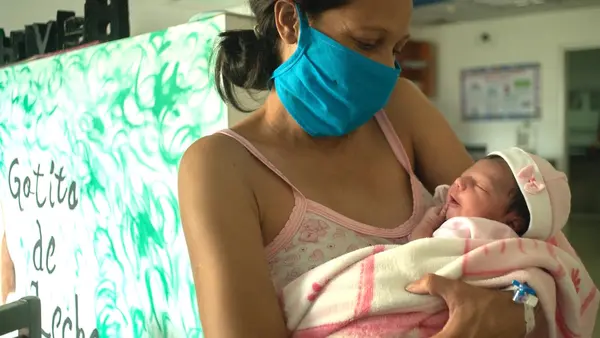A new mother holds her baby, sleepy and full of breast milk, at a UNICEF-supported breastfeeding workshop at a health center in Caracas, Venezuela.