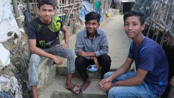 A Rohingya refugee sits with two friends from the local Bangladeshi community — beneficiaries of a UNICEF program building social cohesion..