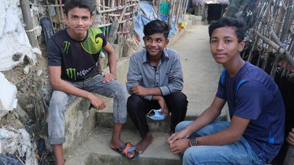 A Rohingya refugee sits with two friends from the local Bangladeshi community — beneficiaries of a UNICEF program building social cohesion..