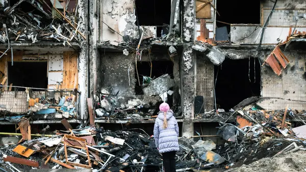 Child in front of a Burnt Down Building
