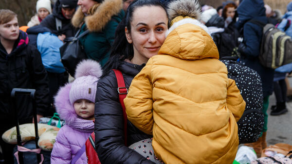 A mother fleeing Ukraine with her family holds one of her children as they wait to cross the border into Slovakia in March 2022.