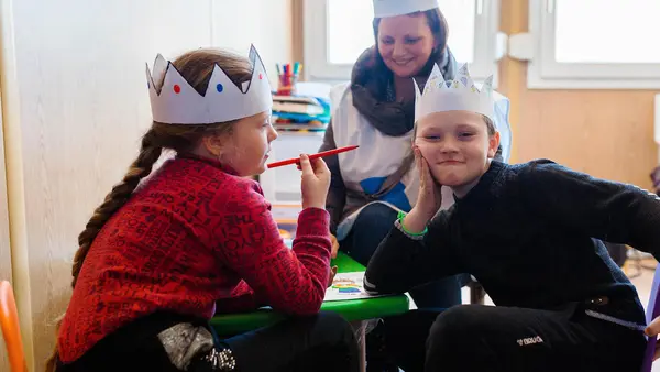 On March 19, 2022, Ivan, right, and his sister, Sofia, from Mariupol, Ukraine, play with a Blue Dot psychologist in a child-friendly space, located in the Blue Dot hub at the Palanca border crossing in the Republic of Moldova.
