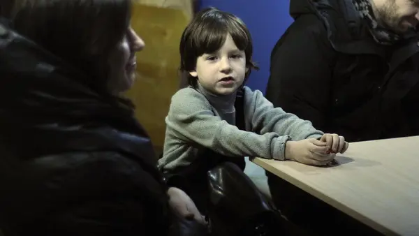 Davyd, 7, sits with his mother and uncle at a temporary shelter in a Kyiv church in March 2022. 