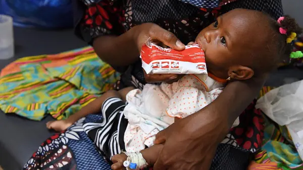 Konata Karko, a 24-year-old mother of two, feeds her acutely malnourished 1-year-old daughter, Mariam, with Ready-to-Use Therapeutic Food at the UNICEF-supported Health Center in Bobo-Dioulasso, southwestern Burkina Faso on May 12, 2022. 