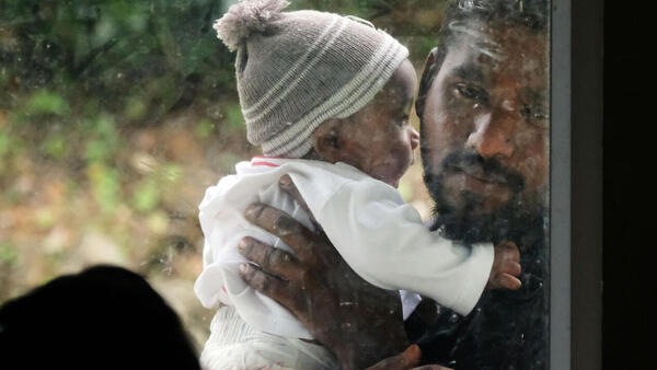 Murugayya Gunasekara, 30, holds his child outside the UNICEF-supported health clinic in the tea estate area in Hatton, central Sri Lanka. 