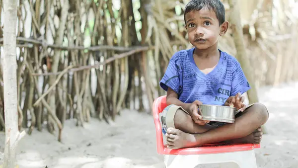 On July 5, 2022, 5-year-old Thulakshan eats his meal while sitting outside his house in the village of Devapuram, Batticaloa, Sri Lanka. 