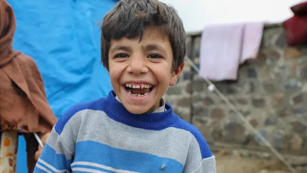Boy smiles outside of the camp where he lives since their homes were destroyed in recent flash floods