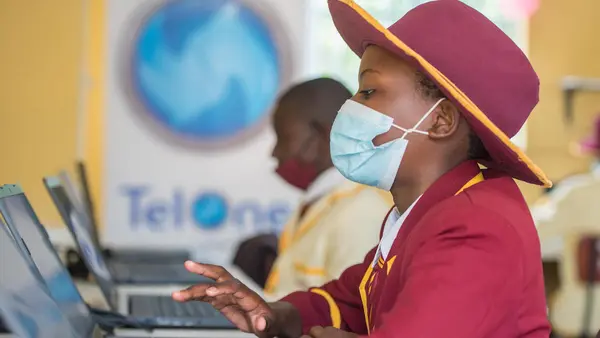 Girl in Hat and COVID Mask Using Computer