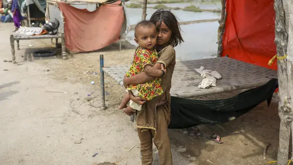 On Sept.2, 2022, six-year-old Vaidya holds her baby sister Nera beside the temporary shelter where she and her family are living in Mirpur Khas District, Sindh Province, Pakistan. 