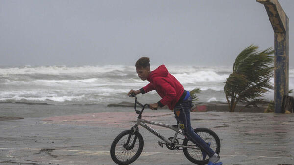 A youth rides his bike in Nagua, Dominican Republic, on Sept. 19, 2022, as Hurricane Fiona passes through the country. 